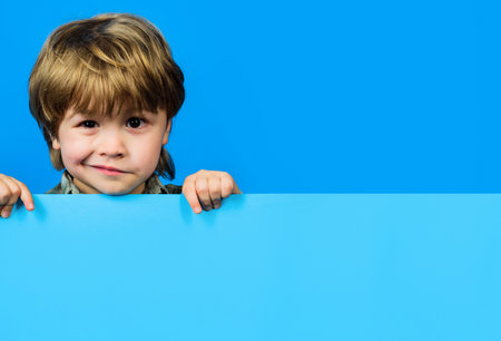 Cute little child with empty advertising board. Little boy holds blank advertising banner with copy...