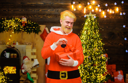 Christmas and New Year holidays. Christmas present. Smiling bearded man in Santa Claus costume with...