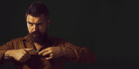 Man in barbershop. Barber shows sharp blade of vintage straight razor. Barber shop. Handsome...