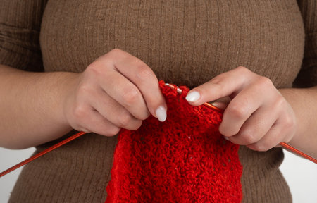 Knitting and needles in hand with red yarn in hands. Knitting needles for cozy handmade textile....