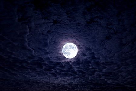 Full moon with dramatic night clouds. Moonlight on dark cloudy sky. Full moon in night. Mystical...