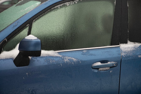 Ice covering vehicle glass outdoors. Frozen car with ice and snow in winter. Icy car extreme cold weather. Frozen vehicle with frost and ice. Winter car freezing. Iced automobile detail.の写真素材