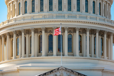 American flag near Capitol with columns in Washington DC. Capitol with American flag as political symbol. US flag on Capitol with movement. Capitol with American flag for democracy background.の写真素材