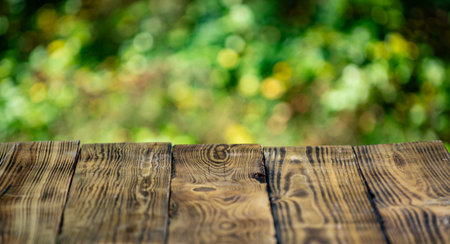 Empty wooden desk top with green tree background. Wooden background with green nature. Wooden rustic...