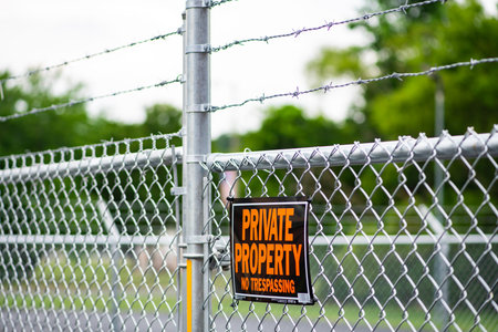 No trespassing sign on fence. Private property with warning sign. No trespassing warns every visitor. Security barrier displays no trespassing. Private gate enforces no trespassing.