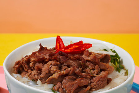 rice noodle with pork and chili in white bowl on colorful background