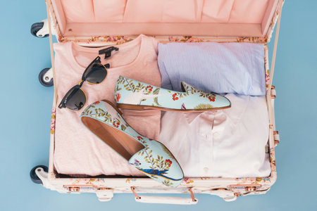 top view of female shoes and sunglasses in suitcase isolated on blue backgroundの写真素材