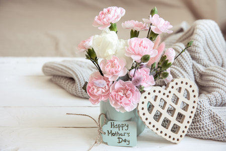 A festive composition with fresh flowers in a vase, decorative elements and a wish for a happy...