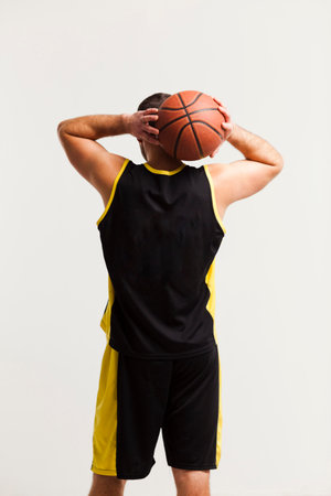 Basketball player in black and yellow sportswear with ball on white backgroundの写真素材