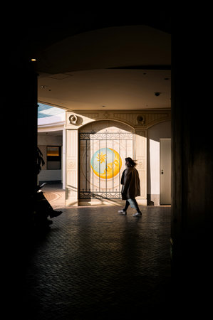 Silhouette of a woman in a coat entering the entrance of a hotel