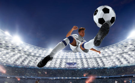 Young football player in jump on the field of stadium under blue skyの写真素材