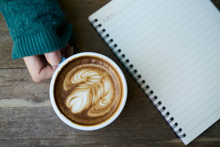 Coffee cup with notebook on wooden table, vintage tone.の写真素材