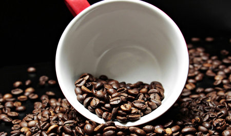 Coffee beans in a white cup on a black background.