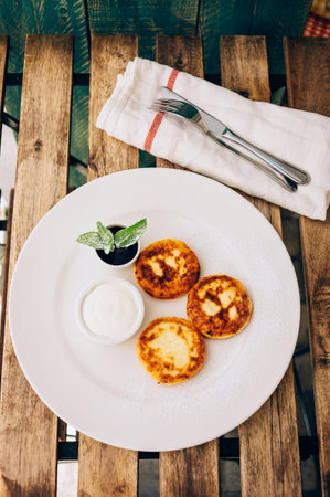 Cottage cheese pancakes with sour cream and mint on a wooden tableの写真素材