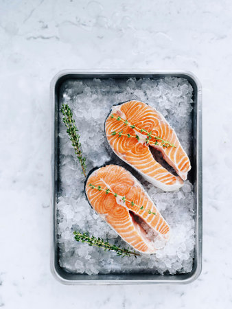 Raw fresh salmon steaks on ice with rosemary, top viewの写真素材