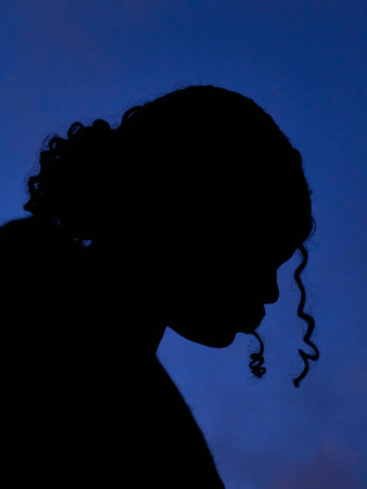 Silhouette of a young girl in profile on a blue backgroundの写真素材