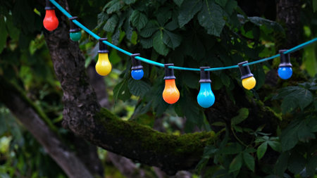 Colourful light bulbs hanging on a rope in a garden.