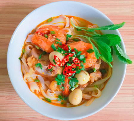 Thai spicy noodle soup with shrimp and vegetables on wooden table