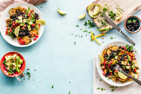Mexican spicy salad with black beans, tomatoes, avocado, cucumber and lime on blue background.