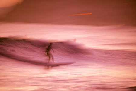 Surfer on the beach at sunset. Long exposure. Motion blur.