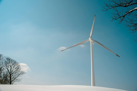 Wind turbines in the middle of the snow-covered field against the blue skyの写真素材