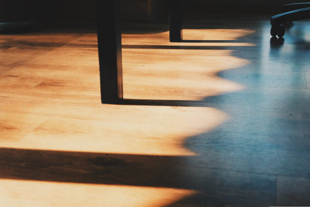 Wooden floor and chair in a room with sunlight and shadow.