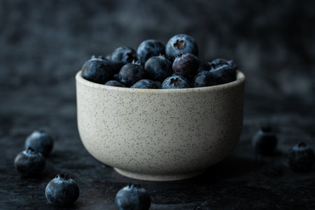 Fresh blueberries in a bowl on a dark background. Toned.