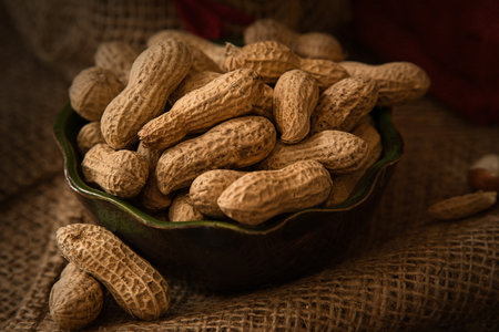 Peanuts in a bowl on a burlap background. Selective focus.