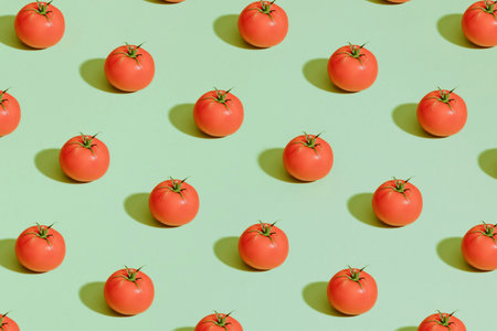 Creative pattern made of tomatoes on green background. Minimal summer concept.