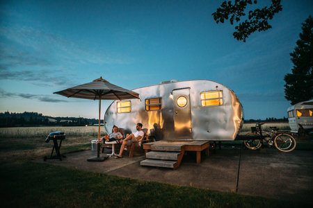 Family on vacation in motorhome. Man and woman sitting near camper trailer.