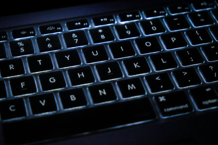 Close up of a black computer keyboard on a dark blue background.