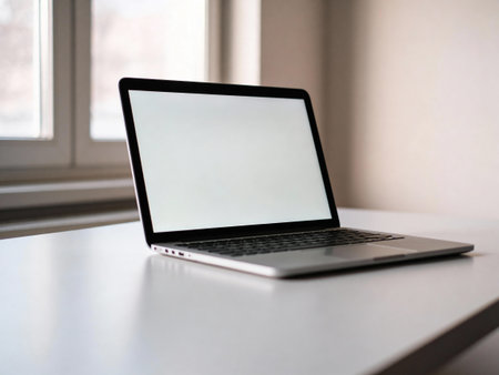 Laptop with blank screen on a white table in front of window