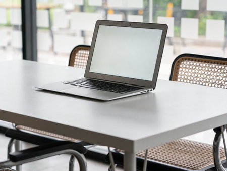 Laptop computer with blank screen on table in cafe, stock photo