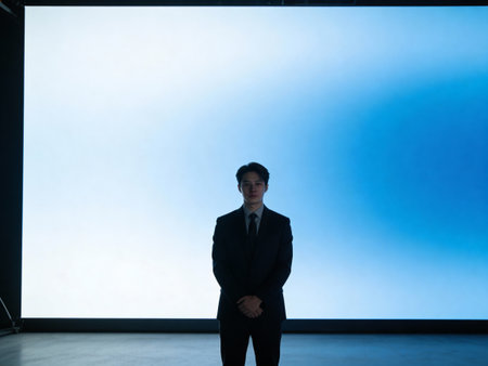 Businessman standing in front of a big white screen with copy space