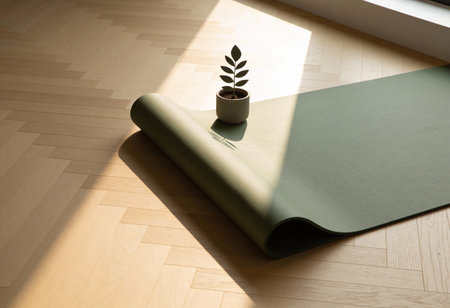 green yoga mat and plant in a pot on a wooden floor.