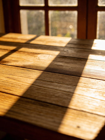 wooden floor in front of a window with sunlight and shadow.