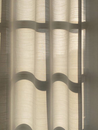 Curtain with shadow in sunlight, close-up of window.