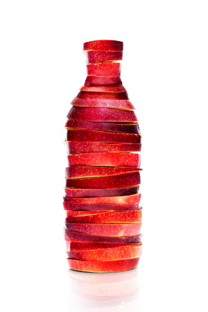 Bottle made from red sliced apples on whiteの写真素材