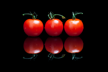 Three tomatoes on a black shiny backgroundの写真素材