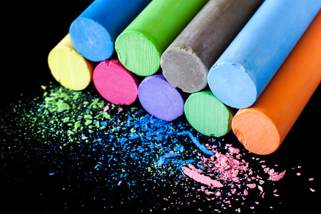 Colored chalk in variety of colors stacked on each other on a black background