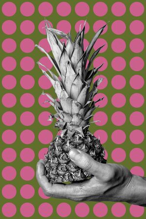 Black and white hand with half pineapple on a green background with pink circles. Collage art.の写真素材