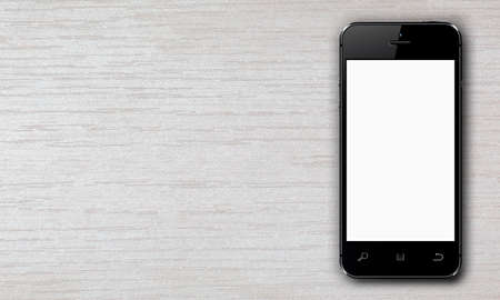 Black smartphone with white blank screen lying on a wooden table