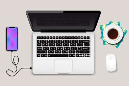Laptop with phone connected to wire and cup of coffee on a tableの写真素材
