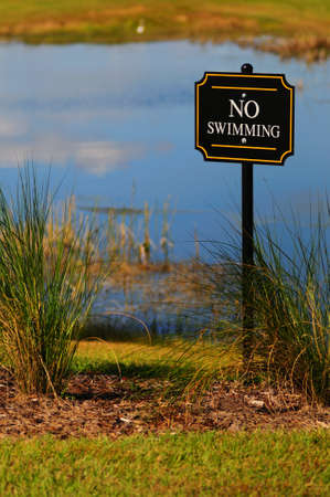 No swimming sign posted in front of a small body of waterの写真素材