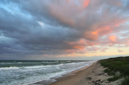 Storm clouds blowing over shore of unspoiled Florida beach at sunset.の写真素材