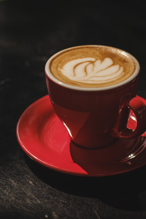 Coffee cup with latte art on black wooden table.の写真素材