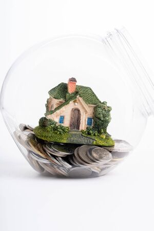 Miniature house in jar full of coinsの写真素材