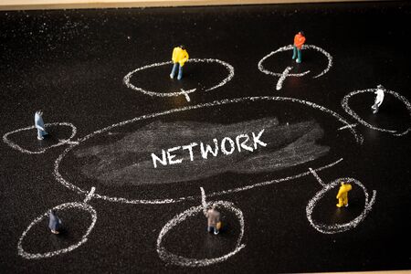 Business concept: Networking. A group of miniatures people on a chalkboard with "NETWORK" wordingsの写真素材
