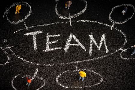 Teamwork concept: a group of miniatures person on a chalkboard with "TEAM" wordingsの写真素材