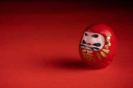 Daruma doll on red background, japanese doll